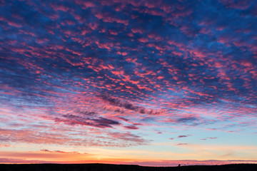 Fototapeta premium Vivid sunrise clouds over badlands formation in Theodore Roosevelt National Park, North Dakota, USA