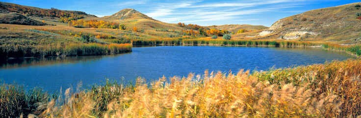 USA, North Dakota, Lewis & Clark SP. Autumn light slants over this deep blue pond in Lewis & Clark...