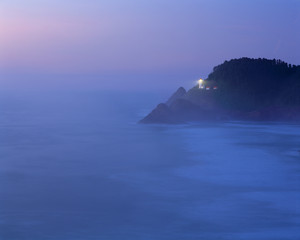 USA, Oregon, Heceta Head. Blue fog on the Oregon Coast makes the beacon of Heceta Head Lighthouse a...