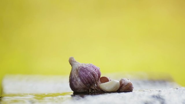 Fresh head of garlic on a table under a stream of water.