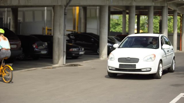 Fearless teenager riding bike right in front of car, driver stopping on time
