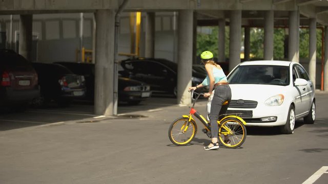 Girl on bicycle crossing roadway ignoring cars, risk of vehicle collision