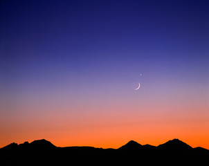 USA, Oregon, Bend. A crescent moon and Venus hang above the silhoutted Cascade Range, Oregon.