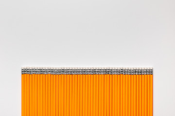 A bunch of pencils aligned in a straight line on white background , shot from above.