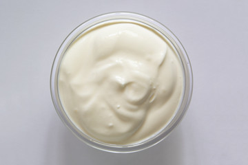 Yogurt or sour cream in a glass bowl on gray background