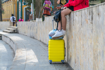 Yellow suitcase of traveler sit on roadside. Travel concept