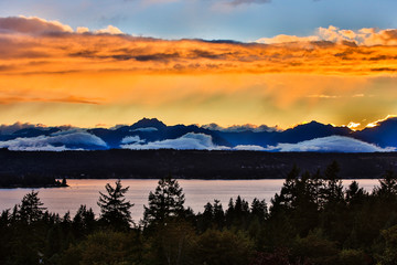 Fototapeta na wymiar Bremerton, Washington State. The Olympic Mountains, featuring Brothers Mountain, bask in a golden, layered, sunset over Dyes Inlet and the Puget Sound