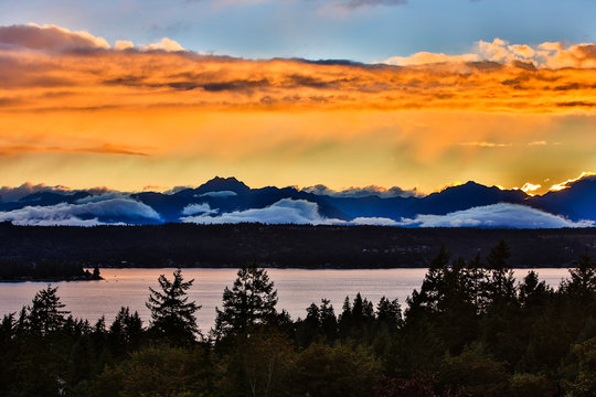 Bremerton, Washington State. The Olympic Mountains, featuring Brothers Mountain, bask in a golden, layered, sunset over Dyes Inlet and the Puget Sound