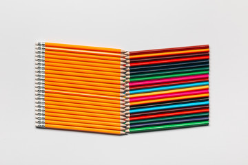 A pack of pencils next to a pack of wooden crayons on white background, shot from above.