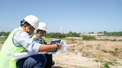 portrait of two engineer's or architect's dress with hardhat, safety helmet and safety vest have a meeting outdoors
