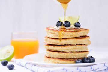 Pouring honey on oatmeal pancake with blueberry
