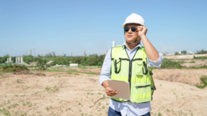 close up bottom front view of male engineer walking and holding tablet computer on bright blue skyand black eye glasses