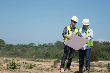 portrait of two engineer's or architect's dress with hardhat, safety helmet and safety vest have a meeting outdoors