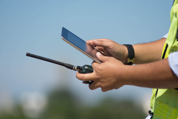 close up bottom front view of male engineer  touch his black tablet computer against bright blue sky  for planing a construction dress with protective vest