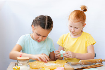 Two children a girl make cookies from dough. Two funny cheerful girls. Natural homemade food.
