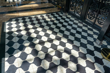 Black and white checkered floor grunge tiles marble surface at public place with interiors and people legs