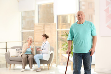 Fototapeta na wymiar Elderly man with cane in nursing home, space for text. Assisting senior generation