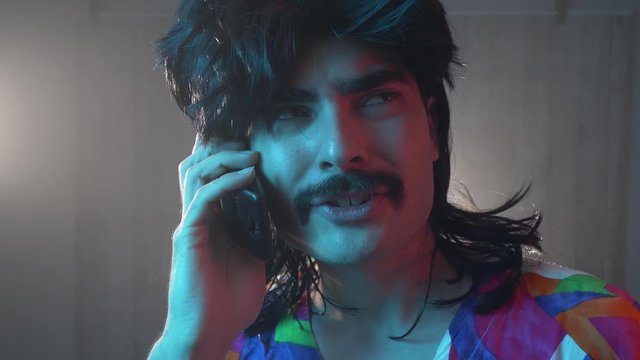 Man with mustache and mullet from the 70s 80s 90 talking on his retro cell phone. Vintage concept.