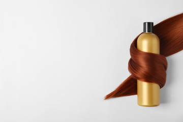 Shampoo bottle wrapped in lock of hair isolated on white, top view. Natural cosmetic products