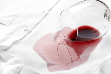 Overturned glass and spilled exquisite red wine on white shirt. Space for text