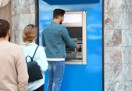 Young people standing in queue to cash machine outdoors