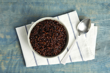 Flat lay composition with delicious cooked brown rice on color wooden table