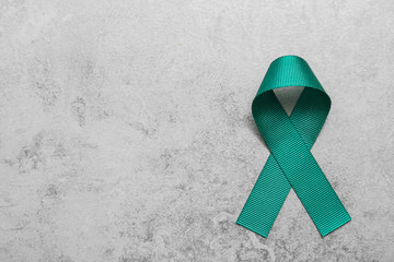 Teal awareness ribbon on grey background, top view with space for text. Symbol of social and medical issues