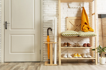 Fototapeta na wymiar Cozy hallway interior with wooden shelving unit. Stylish design idea