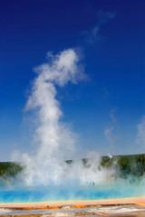 National Park visitors in mist and colorful red bacterial mat around perimeter of Grand Prismatic Spring, Midway Geyser Basin, Yellowstone NP, Wyoming.