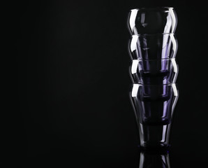 Stack of empty colorful glasses on black background, space for text