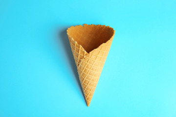 Empty wafer ice cream cone on blue background, top view