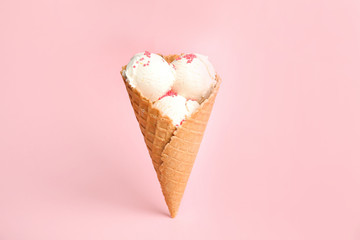 Delicious vanilla ice cream in wafer cone on pink background