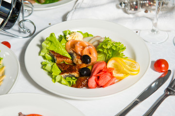 Restaurant dish of fish with olives and lemon on a table in a plate.Cold appetizer.