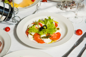 A restaurant dish of curd cheese with tomatoes and olives on a table in a plate. Cold appetizer.