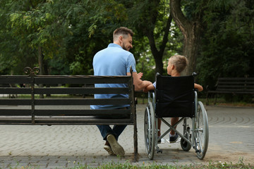 Father with his son in wheelchair at park