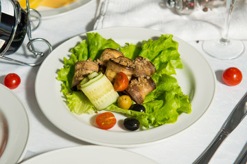 A restaurant dish of stuffed eggplant and olives on a table in a plate. Cold appetizer.