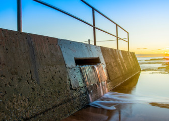 Overflow water flowing out of an ocean beachside pool