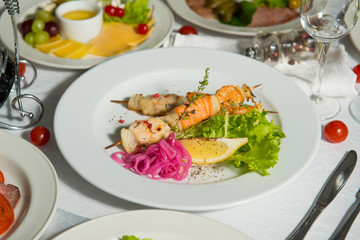 Skewers of fish with a slice of lemon in a plate on a table in the interiors of the restaurant. Cold appetizer.