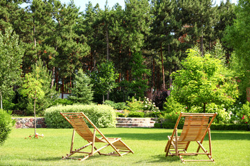 Wooden deck chairs in beautiful garden on sunny day