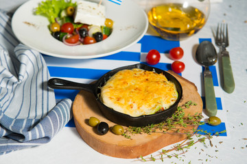Julienne and greek salad on the table with flag of greece. Lunch at the restaurant.