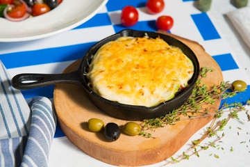 Mushroom julienne with olives on a table against the background of the flag of Greece close-up.