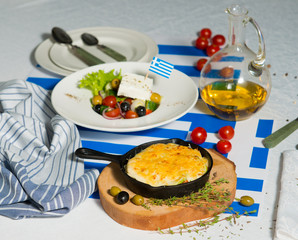Julienne and greek salad on the table with flag of greece. Lunch at the restaurant.