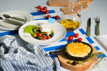 Julienne and greek salad on the table with flag of greece. Lunch at the restaurant.