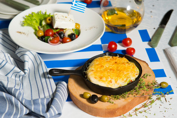 Julienne and greek salad on the table with flag of greece. Lunch at the restaurant.