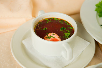 Red borsch in a plate in a restaurant interior closeup.