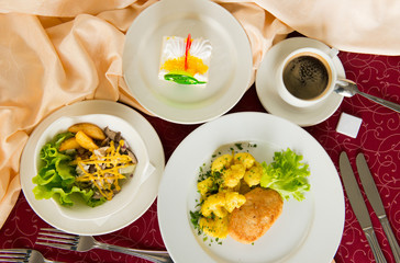 Three-course business lunch on a beige tablecloth in a restaurant top view.