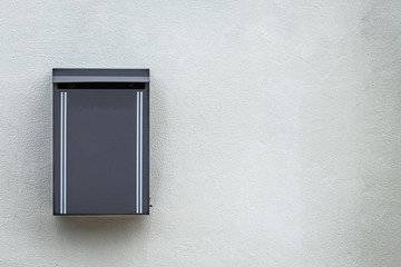 Gray metal mailbox mounted on the cement wall