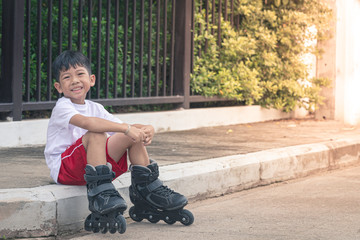 Boy asia sitting smiling at rollerblade shoes