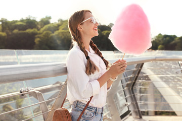 Young woman with cotton candy outdoors on sunny day