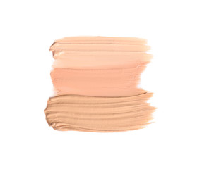 Samples of different foundation shades on white background, top view